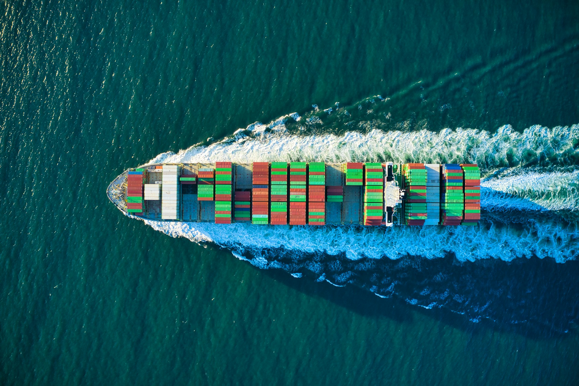a picture of a ship fully loaded with containers travelling in the sea.